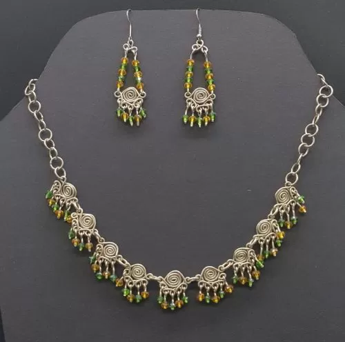 Juego de collar y aretes elaborado con plata alemana y cristales verde y amarillos